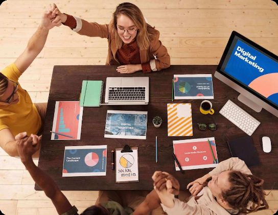 A team celebrating around a table covered with digital marketing reports